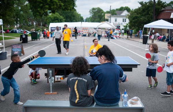 Kids playing on the Temporary Table Tennis Trailer at a street festival with adult onlookers on bench.-photo Bruce Silcox