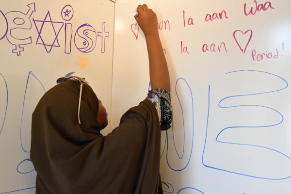 A woman with a hijab writing on a whiteboard