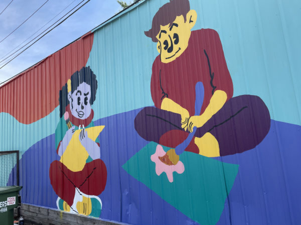Colorful mural of cartoon people painting and coloring by Discover Dope