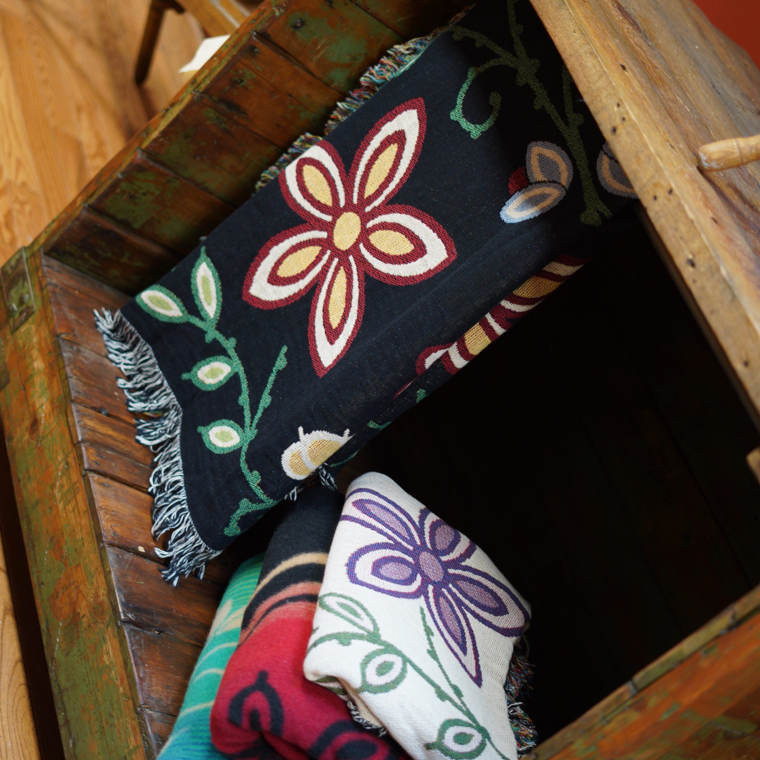 A photograph of colorful blankets in a wooden box