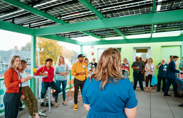A crowd of people gathered on a rootop patio with a green re